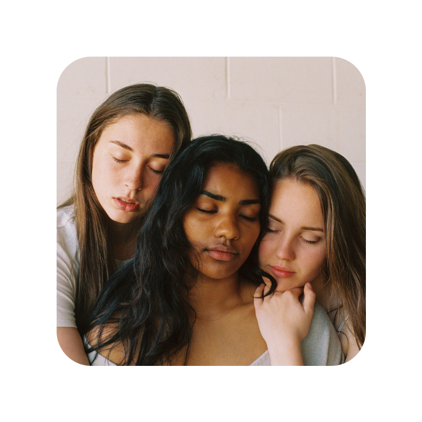 Two white people on the shoulder of a brown person while closing their eyes.